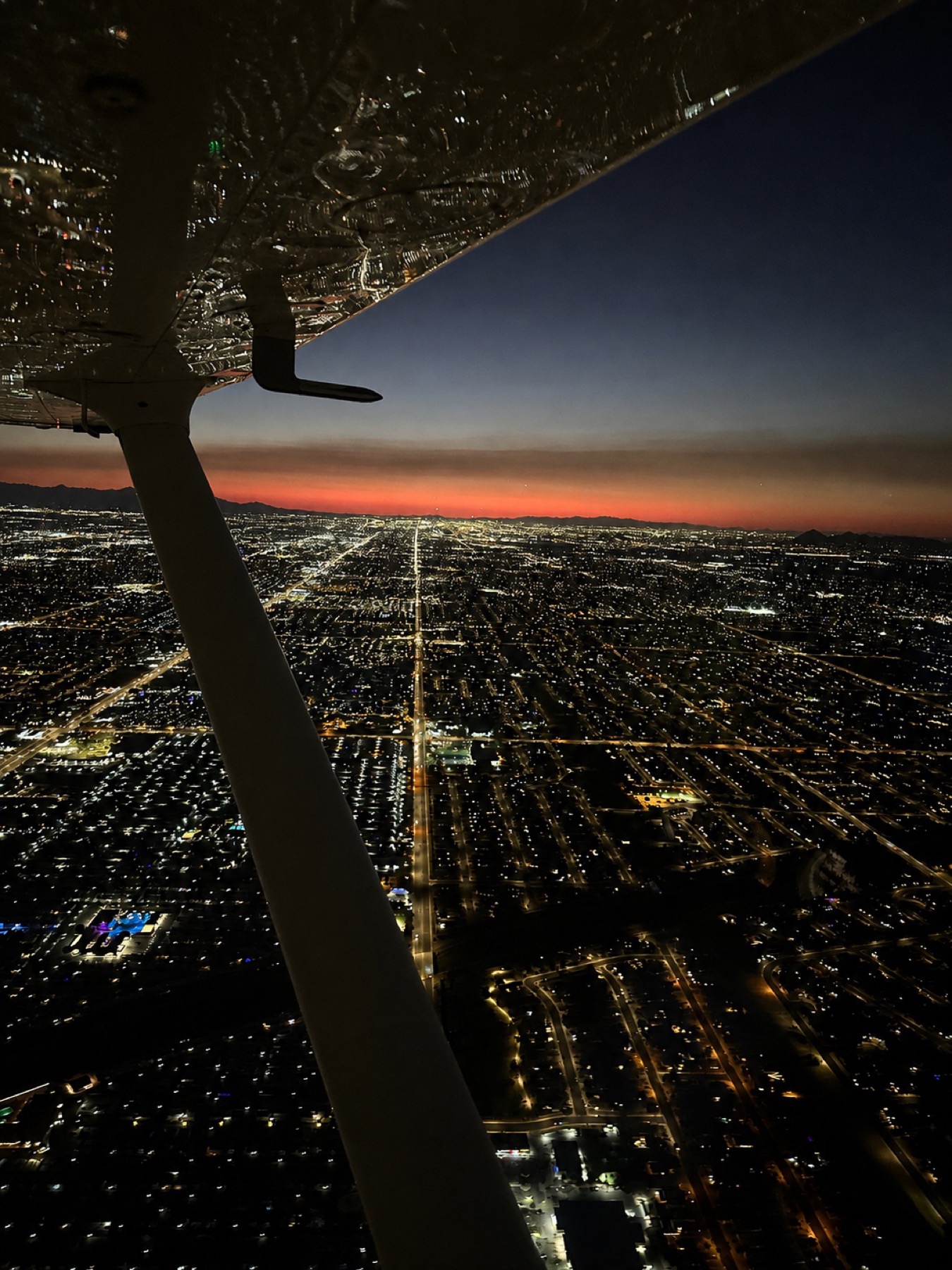 Wing view over the city grid lit up at dusk